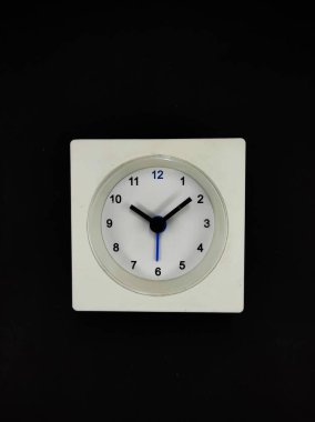 Siyah bir arkaplanda izole edilmiş beyaz kare bir saatin fotoğrafı