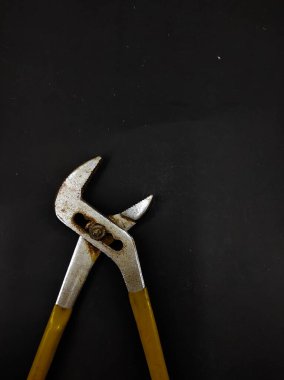 Siyah arka planda ayarlanabilir paslı pense fotoğrafı var.