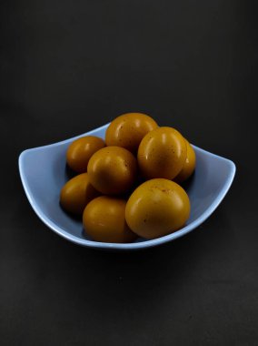 Siyah arka planda izole edilmiş mavi bir kasedeki birkaç yumurtanın fotoğrafı.