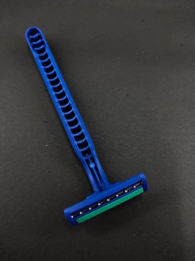 Siyah bir arka planda izole edilmiş iki bıçaklı mavi bir jilet.