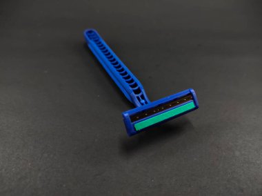 Siyah bir arka planda izole edilmiş iki bıçaklı mavi bir jilet.