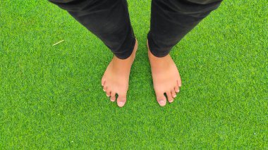 Endonezya 'da yeşil çimen halısı üzerinde siyah kot pantolon içindeki soyut Odaklanmış Ayaklar
