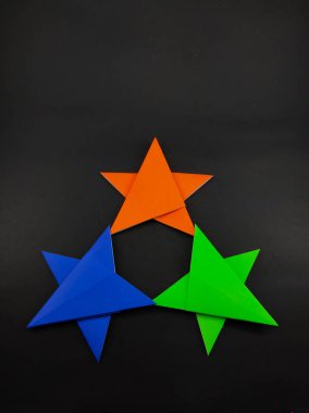 Siyah arkaplanda izole edilmiş origami kağıdından yapılmış soyut odaklanmış üç renkli yıldız