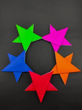 Siyah arkaplanda izole edilmiş origami kağıdından yapılmış soyut odaklanmış beş renkli yıldız