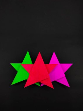 Siyah arkaplanda izole edilmiş origami kağıdından yapılmış soyut odaklanmış üç renkli yıldız