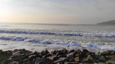 Kıyı, Endonezya 'nın Pangandaran bölgesindeki dalgaları kırmak için kayalarla dolu.