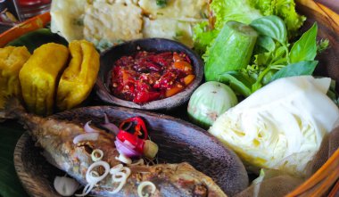 A tray of fish, fried food, fresh vegetables and chili sauce at a restaurant in the Pangandaran area, Indonesia