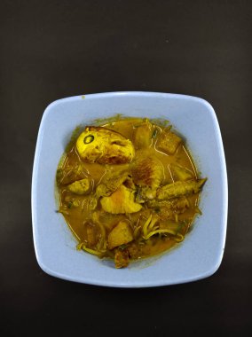 Siyah arka planda izole edilmiş mavi kasede tavuk körisi çorbası.