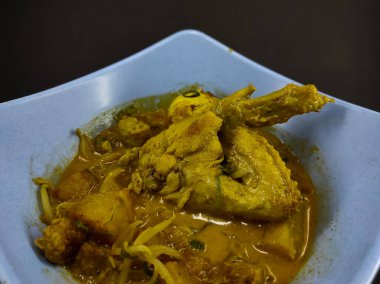 Siyah arka planda izole edilmiş mavi kasede tavuk körisi çorbası.