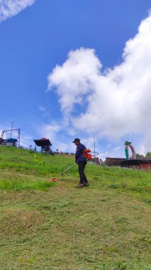 Cicalengka, Batı Java, Endonezya - 11 Haziran 2022: Temizlik çalışanları Endonezya 'nın Cicalengka bölgesindeki yamaçlarda yabani otları kesiyor