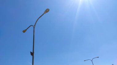 Photo of a lamp post in a city square park in the Cikancung area, isolated on a bright blue sky background - Indonesia.
