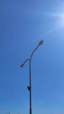 Photo of a lamp post in a city square park in the Cikancung area, isolated on a bright blue sky background - Indonesia.