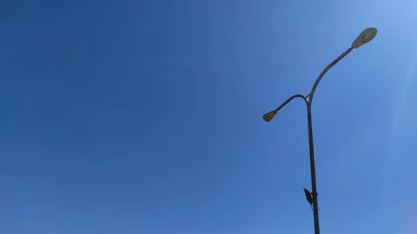 Photo of a lamp post in a city square park in the Cikancung area, isolated on a bright blue sky background - Indonesia.