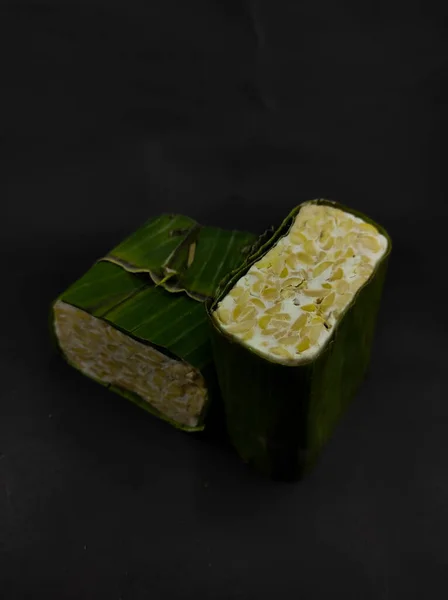 Photo Two Blocks Raw Tempeh Wrapped Banana Leaves Isolated Black — Foto de Stock