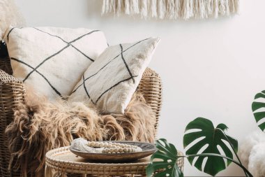 Kahve masasının yanındaki minderli rahat koltuğa yakın görüş. Etnik içerikli oda, boho ev dekorasyonu ve doğal malzeme mobilyası.