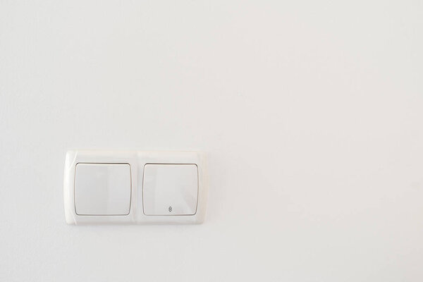 Double light switch button in plastic frame on white copy space wall. Concept of electrical and modern household equipment in living room, office or bedroom