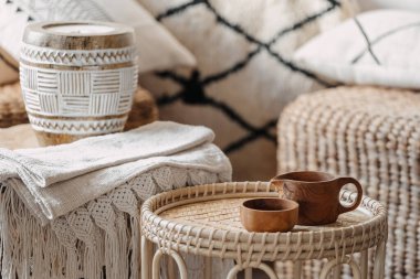 Işıl ışıl ve rahat oturma odasında, arka planda bulanık duran bambu kahve masasında duran iki tahta fincana seçici bir şekilde odaklan. Boho Şık iç mekanında ekolojik malzemeler, mum ve tekstil içeren hasır mobilyalar.