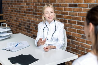Pratisyen hekim klinikteki hastayla konuşuyor. Genç bir kadın hastaneyi ziyaret eder, uzman doktorların detaylı tavsiyelerini dinler, sağlık sorunlarını tartışır. Kadın doktor tedavi planını açıkladı
