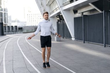İp atlayan, dışarıda antrenman yapan, vücudunu ısıtan ve sokakta koşmaya hazırlanan genç sporcuların tam boy görüntüsü. Mutlu sporcu kardiyo egzersizi yapıyor. Sporda dinamik kavramı
