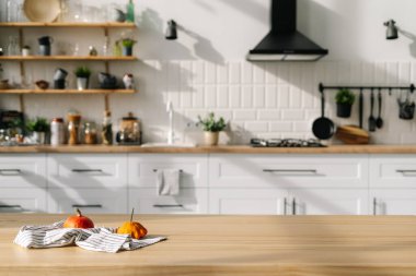 Havlu üzerinde küçük balkabakları olan modern tarz mutfak iç tasarımı. Arka planda çağdaş beyaz mobilya, çatal bıçak, bitki, ev aletleri ve dekor