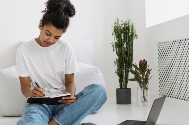 Günlük ya da not defterine notlar yazan, evde çalışan, ödev yapan, üniversite ya da lisede sınava hazırlanan odaklanmış ve gülümseyen genç öğrenci kız. İlham, hayal gücü ve eğitim kavramı