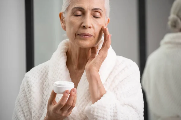 Retrato Mulher Idosa Com Garrafa Creme Nas Mãos Tocando Rosto — Fotografia de Stock