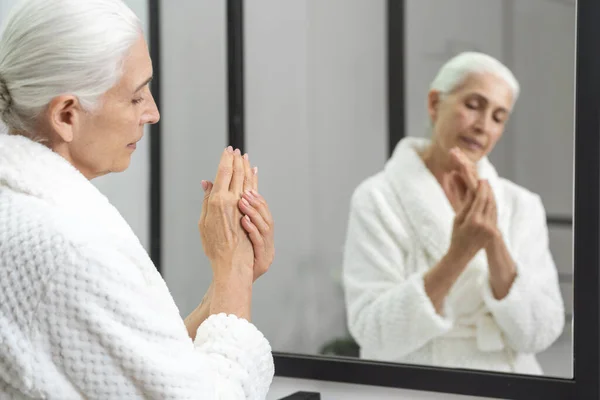 Aynanın Önündeki Bornozlu Yaşlı Kadının Profili Avuçla Ovma Işlemi Güzellik — Stok fotoğraf