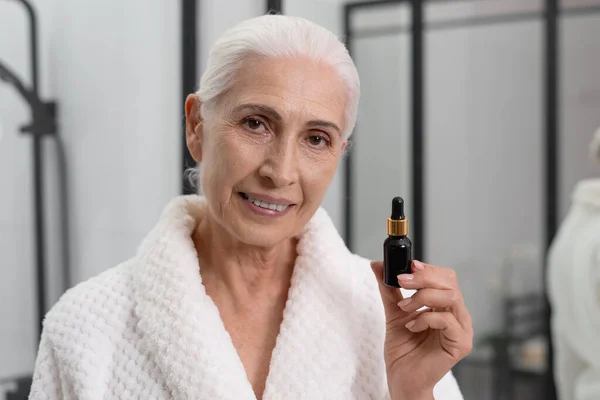 Retrato Una Anciana Mirando Cámara Sosteniendo Vial Suero Cuidado Piel — Foto de Stock