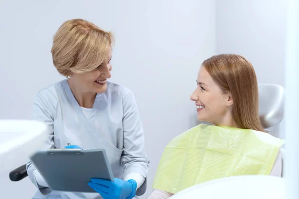 口腔卫生 牙齿保健及预防牙齿清洁的概念 专业的牙医制定治疗计划 在她坐在口腔科椅子上与快乐而微笑的病人交谈 — 图库照片