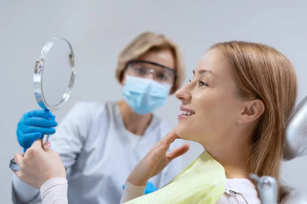 面带微笑的女人在牙医预约时照镜子的侧视图 口服药的概念 Caries Prevention Treatment 牙齿美白或刷牙 — 图库照片