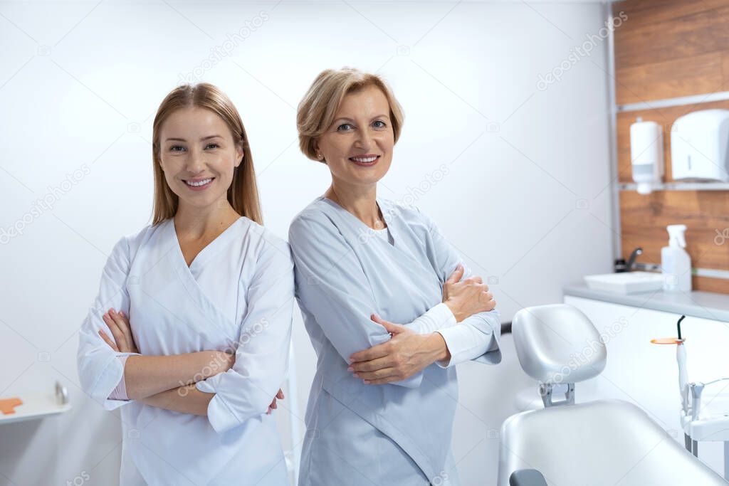 Portrait of smiling doctor and assistant with their backs to each other. Teamwork concept. Healthcare workers. Oral medicine sector. Teeth illness treatment