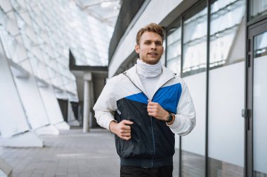 Şehirde koşma kavramı. Koşucu ısınıyor, dışarıda antrenman yapıyor, kardiyo egzersizi yapıyor. Sportif bir adam sokakta koşuyor, vücudunu formda tutuyor. Spor ve sağlıklı yaşam tarzı