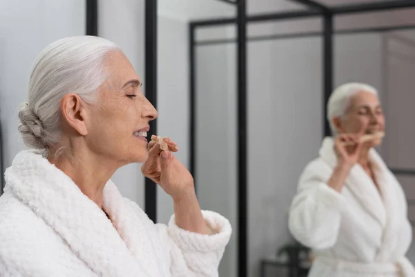 Aynanın Önünde Elinde Diş Fırçası Tutan Yaşlı Bir Kadının Kaliteli — Stok fotoğraf