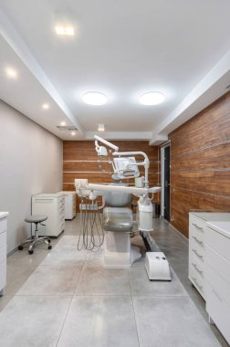 Büyük koltuk kenarı cihazları, mobilyaları ve enstrümanları olan dişçi dolabının modern iç tasarımı. Stomatoloji kliniği. Ağız sağlığı konsepti. Ortodontik hastane odası.