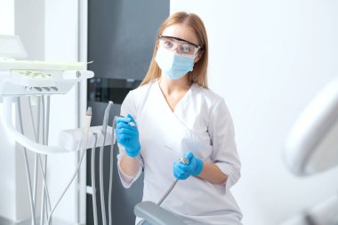 Diş aletleri ve ekipmanların yanında profesyonel stomatolog portresi. Diş tedavisi prosedürü için hazırlık. Ağız ilacı. Diş sağlığı sektörü