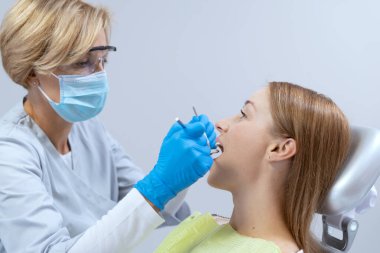 Hastaların dişlerini paslanmaz aletler ve aletlerle tedavi eden profesyonel diş hekiminin yan görüntüsü. Stomatoloji kliniği. Ağız sağlığı sektörü. Diş fırçalama