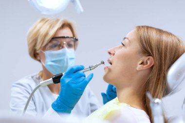 Modern hastanede hastaların dişlerini tedavi eden dişçiler. Stomatoloji kliniği. Ağız sağlığı konsepti. Diş yerleştirme veya beyazlatma işlemi