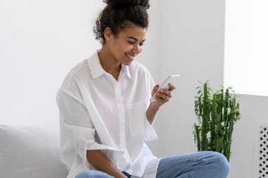 Akıllı telefon kullanarak arkadaşlarıyla sohbet eden sevimli Afro-Amerikan kızın portresi. Çevrimiçi iletişim. Gadgets bağımlılık konsepti. Gençlerin yaşam tarzı.