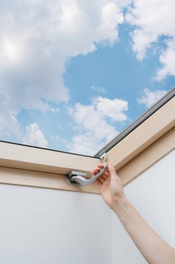 Kadının el ele tutuşmasının dikey fotoğrafı ve çift camlı mansard penceresini ahşap çerçeveye kilitle. Modern evde tavan penceresi. İnşaat ve yenileme konsepti