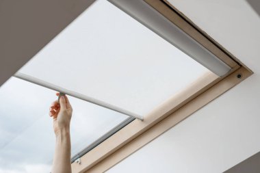 Reklam kavramları. Modern apartmandaki ahşap çerçevenin tavan arası ya da mansard penceresinde elleri açık kadın perdeleri. Evin yeni ve rahat iç tasarımı
