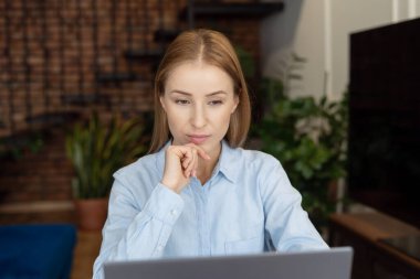 Evde çalışırken dizüstü bilgisayara bakan çekici bir kadının portresi. İş ortağıyla internet üzerinden iletişim kurma süreci. Uzak görev