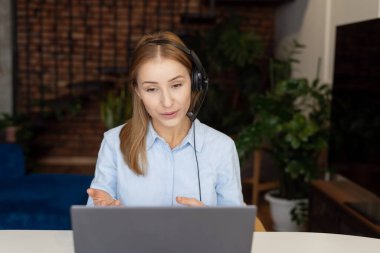 Bilgisayarı ve kulaklığı kullanarak müşteriye danışan güzel ve kendine güvenen bir kadının portresi. Merkez ofis konsepti. Çağrı merkezi operatörü mesleği. Uzaktan kumanda. Müşteri desteği