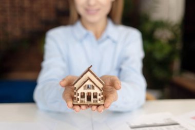 Elinde 3D modelle gülümseyen kadın. Emlakçı mesleği. Satılık konutlar. Gayrimenkul yatırımı. Kiralık banliyö evi