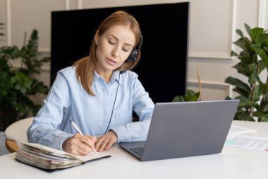 Laptop ve kulaklık kullanan kadın portresi. Evden çalışan çağrı merkezi operatörü. Uzaktan kumanda. Müşteri hizmetleri çalışanı müşteri siparişleriyle ilgilenir