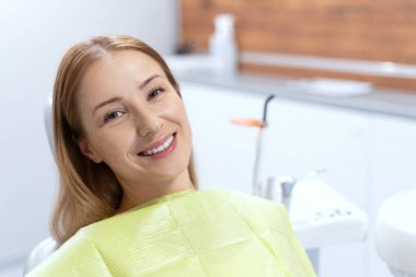 Diş hekiminde dişlerini tedavi ettikten sonra güzel ve gülümseyen bir hastaya yakın çekim. Stomatoloji kliniği. Ağız ilacı. Diş beyazlatma sonucu