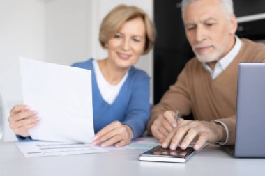 Yaşlılar faturalar için hesaplanmış harcamalar, aile hesapları, vergi ödemeleri ve ipotek kredileri için evlendiler. Yaşlı çift emeklilik birikimleri, hesap makinesine seçici odaklanma