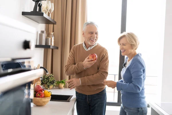 退職シニアカップル笑って 一緒に週末を過ごす 午前中に明るいキッチンに立っている 健康的な食べ物を準備し 広い笑顔で 瞬間を楽しむ不注意な幸せな家族 — ストック写真