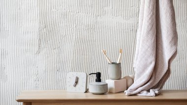 Banyodaki ahşap raf modern çalar saat, sabun makinesi ve bambu diş fırçası seramik bardakta diş bakımı için temiz banyo havlusuna yakın. Sabah kişisel bakım ve güzellik rutin konsepti