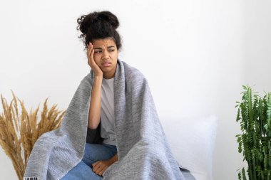 Evinde kendini kötü hisseden, battaniyeyle örtünen genç, üzgün Afrikalı Amerikalı. Grip belirtileri. Sağlık sorunları. Tıp konsepti. Depresyon ve hüsran durumu