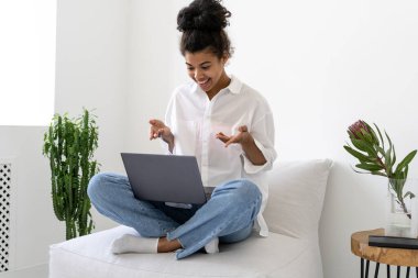 Diz üstü bilgisayarı olan, arkadaşlarıyla görüntülü konuşma yapan neşeli Afro-Amerikan kız portresi. Çevrimiçi iletişim kavramı. Covid19 salgın gerçekliği